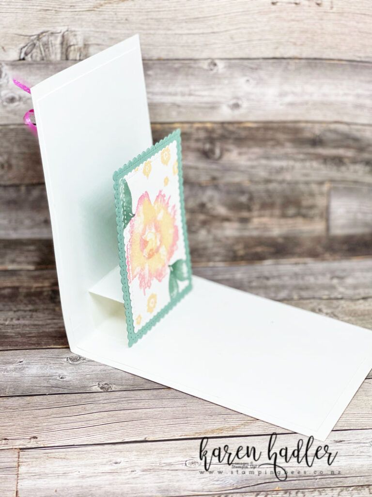 Expressions in Ink Artistically Inked stamp of the large flower image. It has a water colour appearance. The main colour is Pale papaya with Polished pink around the edges. There are two green leaves and a sprinkling of small Pale Papaya Flowers. This is a side view of the inside of the card and the flower is on a Soft succulent base and pops out when opened.