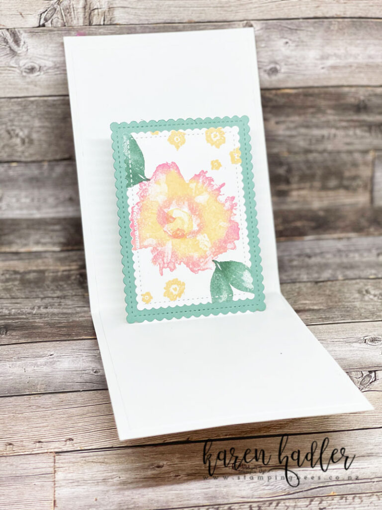 Expressions in Ink Artistically Inked stamp of the large flower image. It has a water colour appearance. The main colour is Pale papaya with Polished pink around the edges. There are two green leaves and a sprinkling of small Pale Papaya Flowers. the inside of the card and the flower is on a Soft succulent base and pops out when opened. This is the front view highlighting the gorgeous flower.