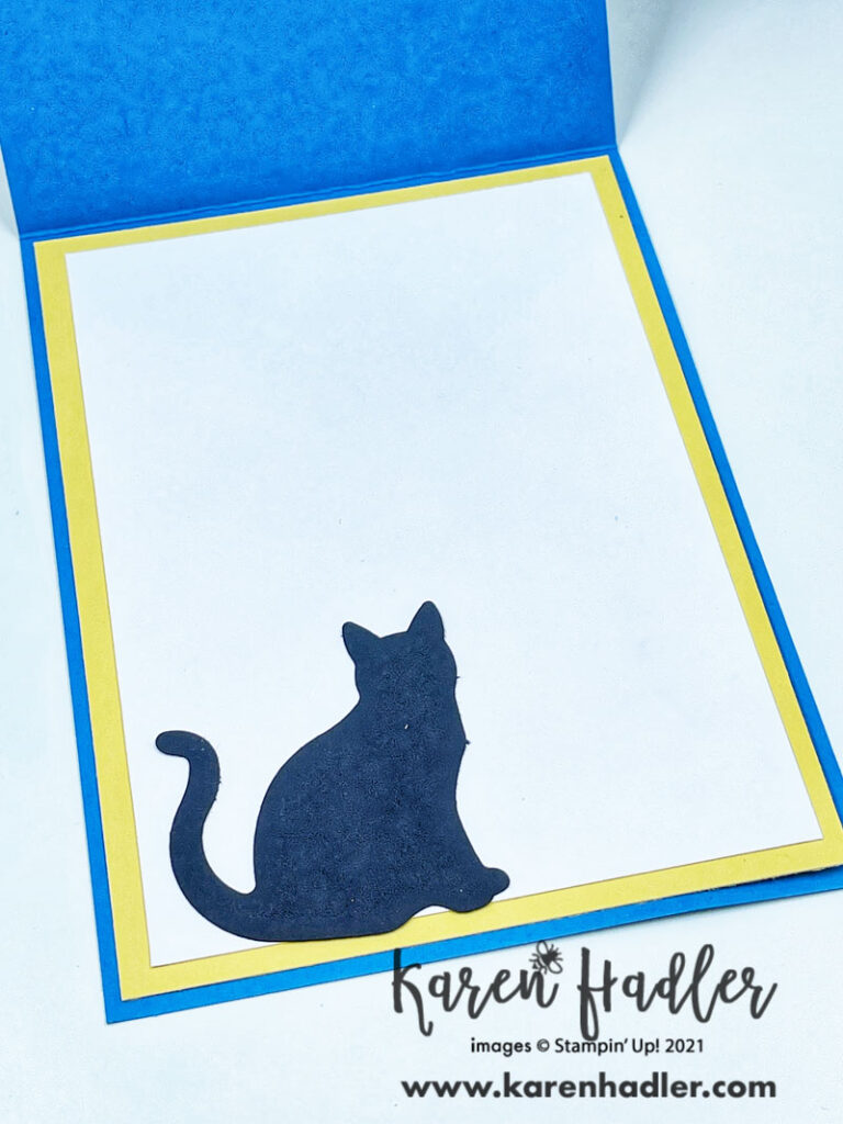 The inside of the card. The base is blue with a yellow mat. On top of the yellow mat is a white mat with a black cat.