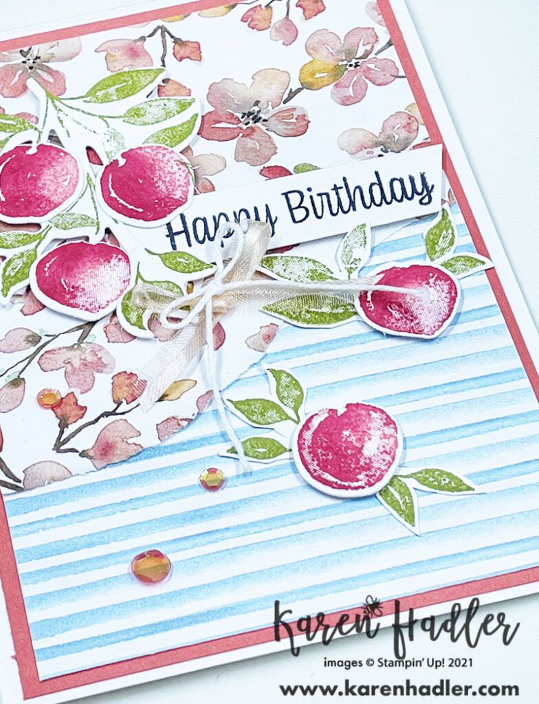A close up ofSweet AsA Peach card on a thick white Card base. A calypso Coral mat. The You're a Peach DSP is ripped in half to highlight both sides. There are 5 red/orange peaches with Pear Pizzaz Green leaves. The Sentiment is stamped in Black on Basic White and reads Happy Birthday.
