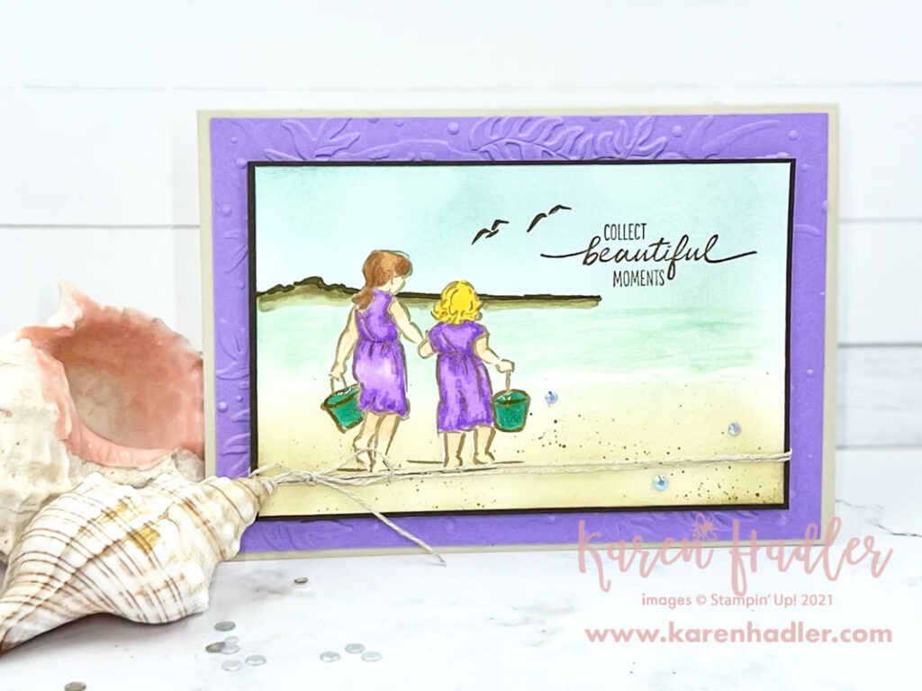 Collect Beautiful Moments by the Seaside. A sand coloured card base with a soft purple mat. On the front is a scene on the beach with two girls holding hands walking towards the water.They each have a green bucket. The sentiment reads Collect beautiful moments