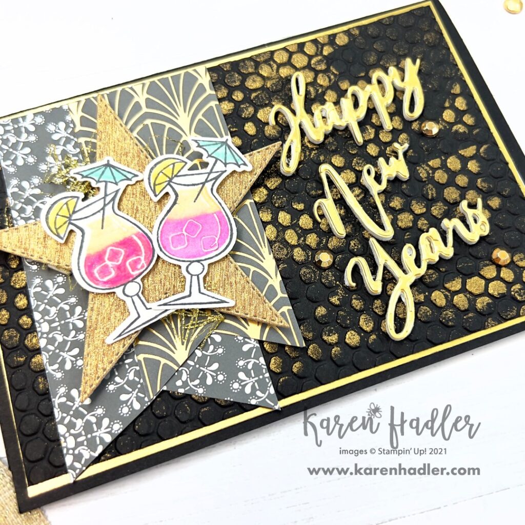 A Picture of a Black Gold and Pink Card with text.This is a closer look at the card. The words say Happy New Years. There is a large Shimmery Gold Star with two Pink cocktails including a lemon and umbrella.