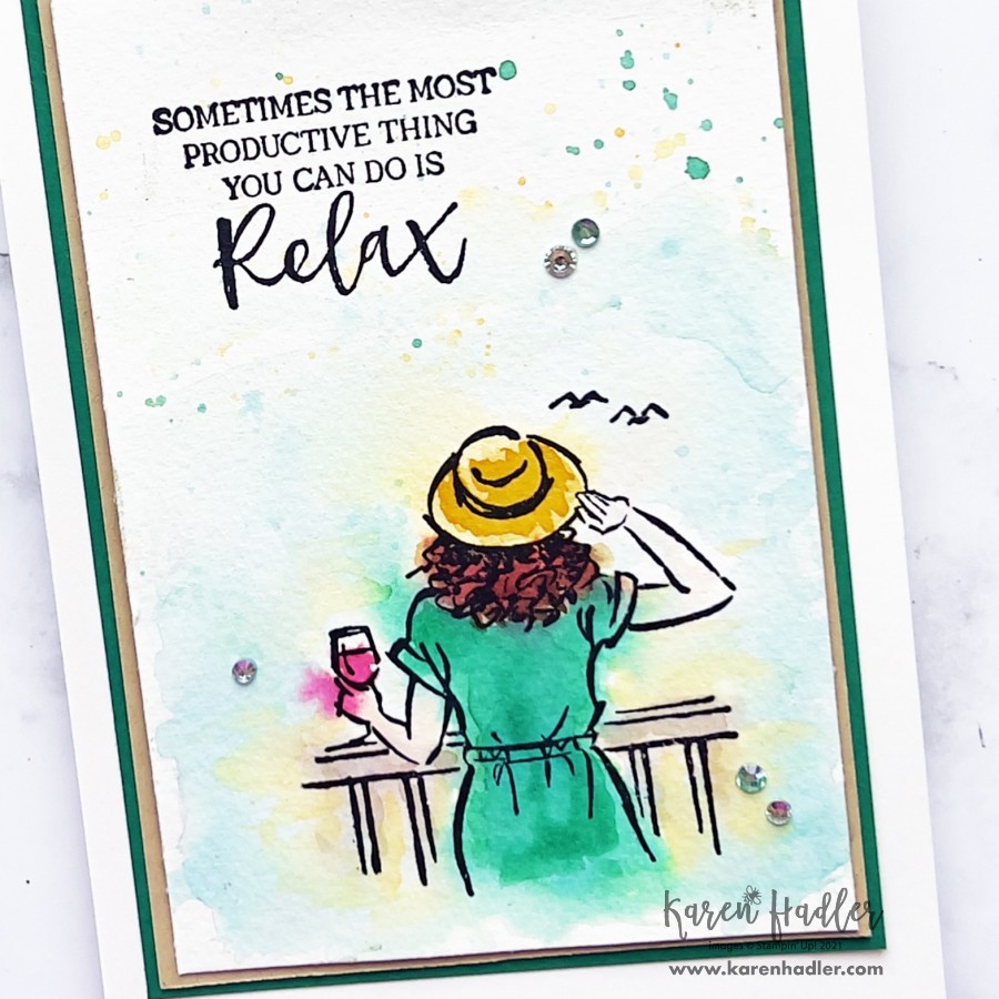 A close up picture of a card that is water coloured with a girl looking out to sea on a sunny day. She has a green dress and yellow hat. The txt says sometimes the most productive thing you can do is relax.