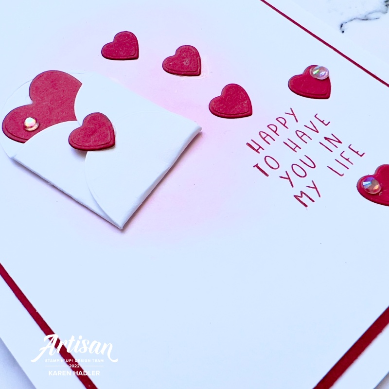 A close up of aA picture of a red and white card with text. The words are Happy to Have you in my life. There is a small white envelope in the centre with red hearts coming out and down the card.