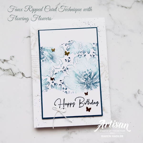 A picture of a card with with text. This is a white and blue card with two tone blue flowers in the middle. The words read Happy Birthday and there is a small white bow.