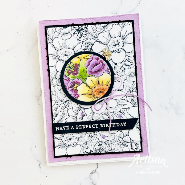 A card with text that reads Have a happy Birthday. The card is covered with black and white stamped flowers with only one area cut out in a circle and coloured with purles, yellows and greens.