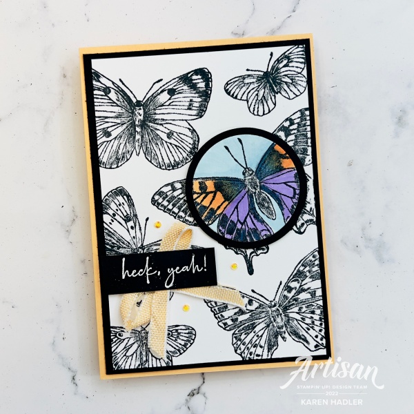 A picture of a card with text that reads heck yeah. The card has large black and white butterflies on it with one butterfly having a circle cut out and coloured with purples and oranges.