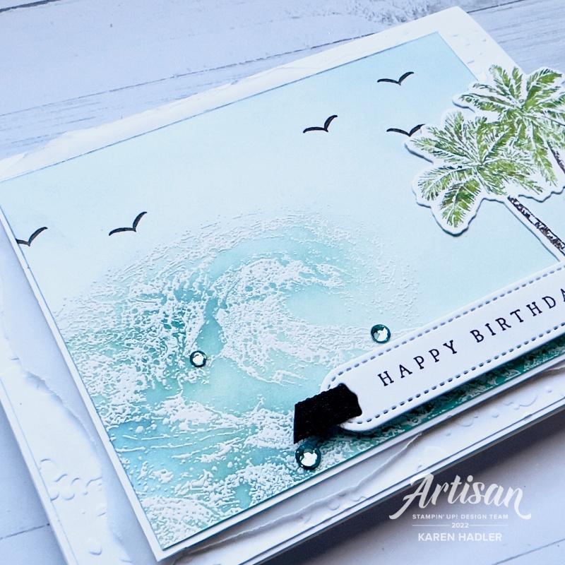 A close up off a birthday card with Palm trees and ocean waves.