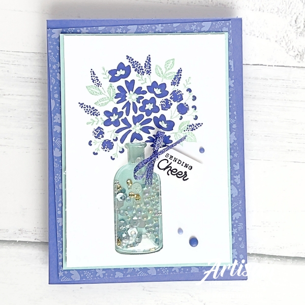 A picture of a purple themed greeting card with a bouquet of flowers in a vintage shaker bottle and the sentiment reads sending Cheers.