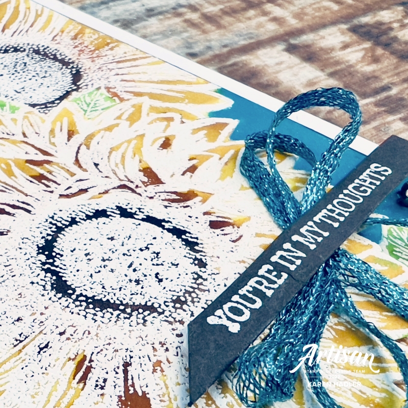 A close up of A picture of a greeting card with a blue background and bright yellow sunflowers. The sentiment reads You're in my thoughts.