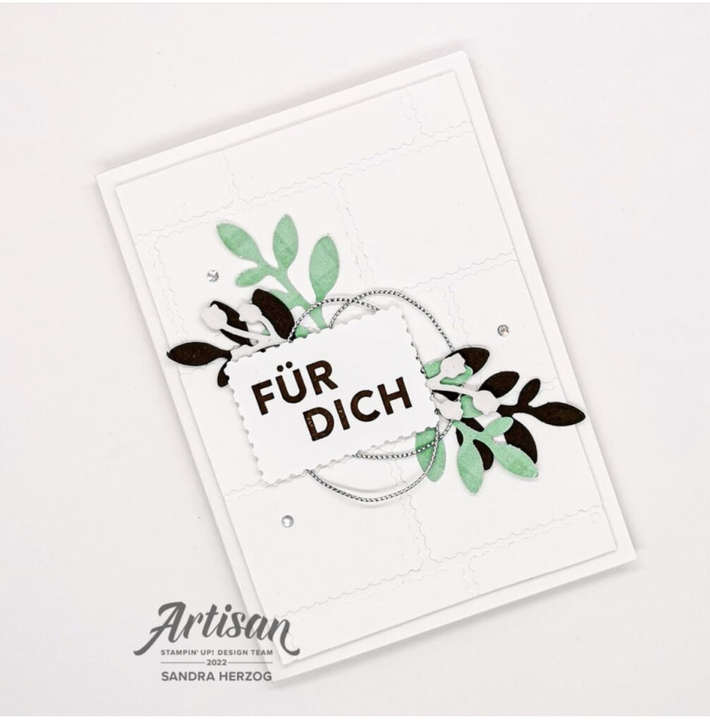 A picture of a white greeting card with foliage mirrored top and bottom.
