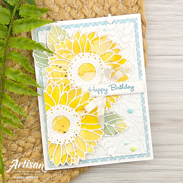 A picture of a Birthday Card with two bright yellow water coloured Sunflowers with a white and blue Gingham background.