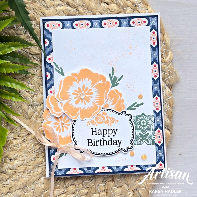 A picture of a greeting card with a blue background some large peach blooms and a sentiment that reads Happy Birthday.