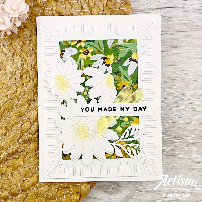 A greeting card that has a white background and in the middle some beautiful Papers os green and yellow depicting daisies. In the foreground are 3 large daisies in white with yellow centres. The sentiment reads You made my day.