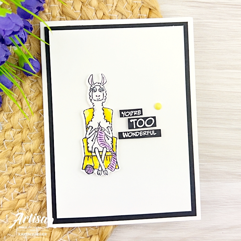 A greeting card with a cute Llama sitting on a yellow chair knitting a purple scarf.
The sentiment white on black card reads You're Too Wonderful.