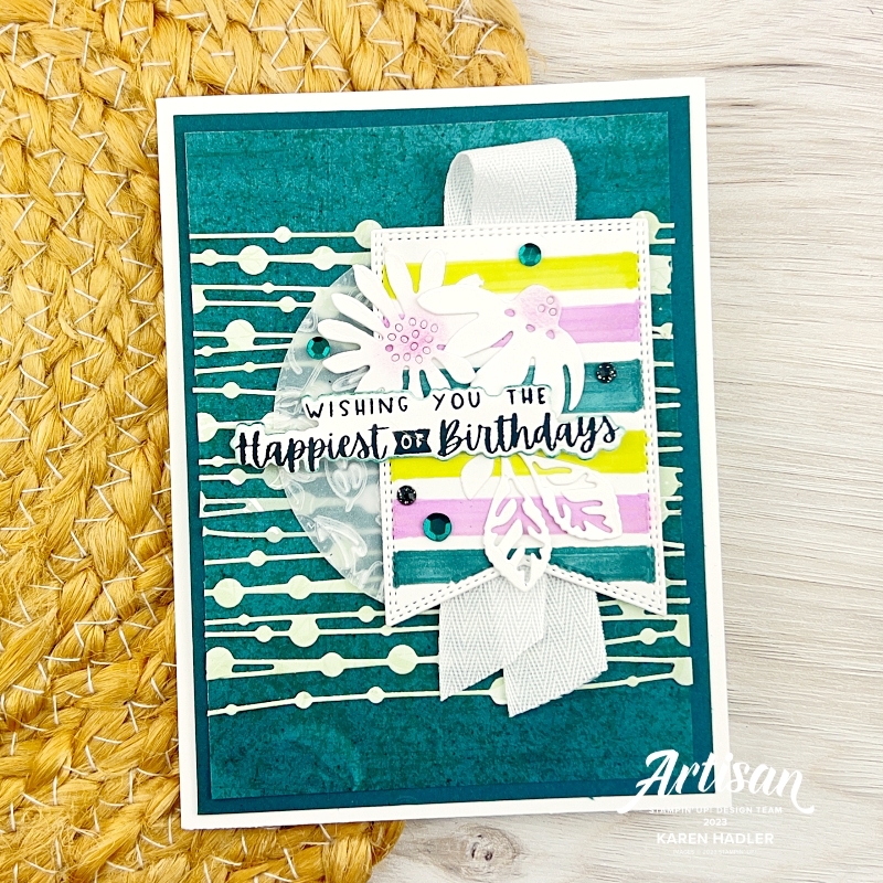 A picture of a Birthday Card. In the background the is stripes and spots. In the foreground there is a tag with, pink, green and yellow stripes. On top of this there is 2 daisies with pink centres. The sentiment reads wishing you the Happiest of Birthdays