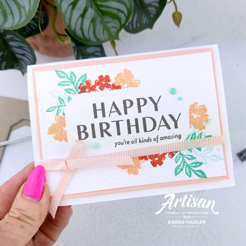 A greeting card with a large Happy Birthday in the middle and in smaller lettering beneath words that read you're all kinds of amazing. This is onl flat card stock and the area around is embossed and stamped with flowers and leaves
