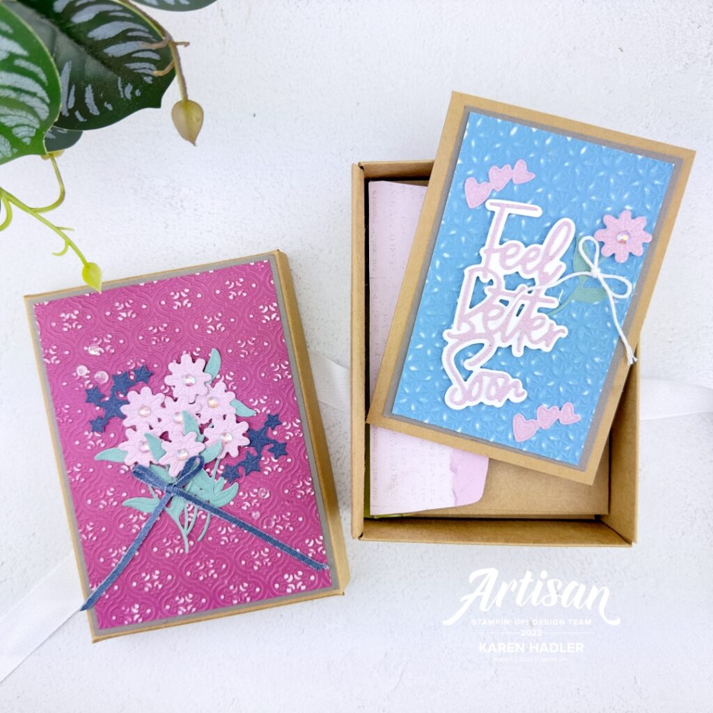The front of a gift box decorated with White center paper that has been embossed and sanded. In the middle is a posy of pink flowers with a blue bow. Top and bottom are some blue Soft Glimmer stars.Plus a Gift Card that is half in the gift box that is blue with a white and pink sentiment that reads Feel Better soon. there is a White Twine bow around a pink flower stem.