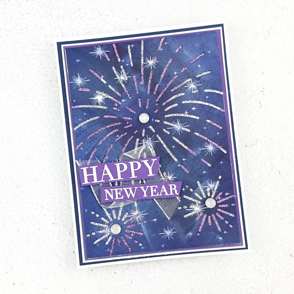 A Greeting card on a white base with a blue then white mat. then purple and silver glimmer paper has been adhered to a white mat and ontop of this is a piece of starry sky imagery Designer Series apaper. The firework shapes have been cut out of this paper to reveal the shimmery paper below. The the sentiment to the left reads Happy new Yaer and each firework has a silver glimmer embellishment.