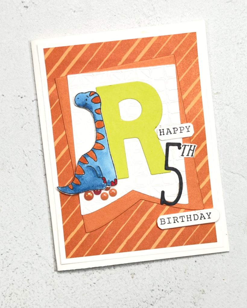 A age related boys Birthday card for a 5 year ol. The colours are orange and green with a large lemon Lime twist letter R on the left of this is a blue and orange Dinosaur. The sentiment reads happy Birthday.