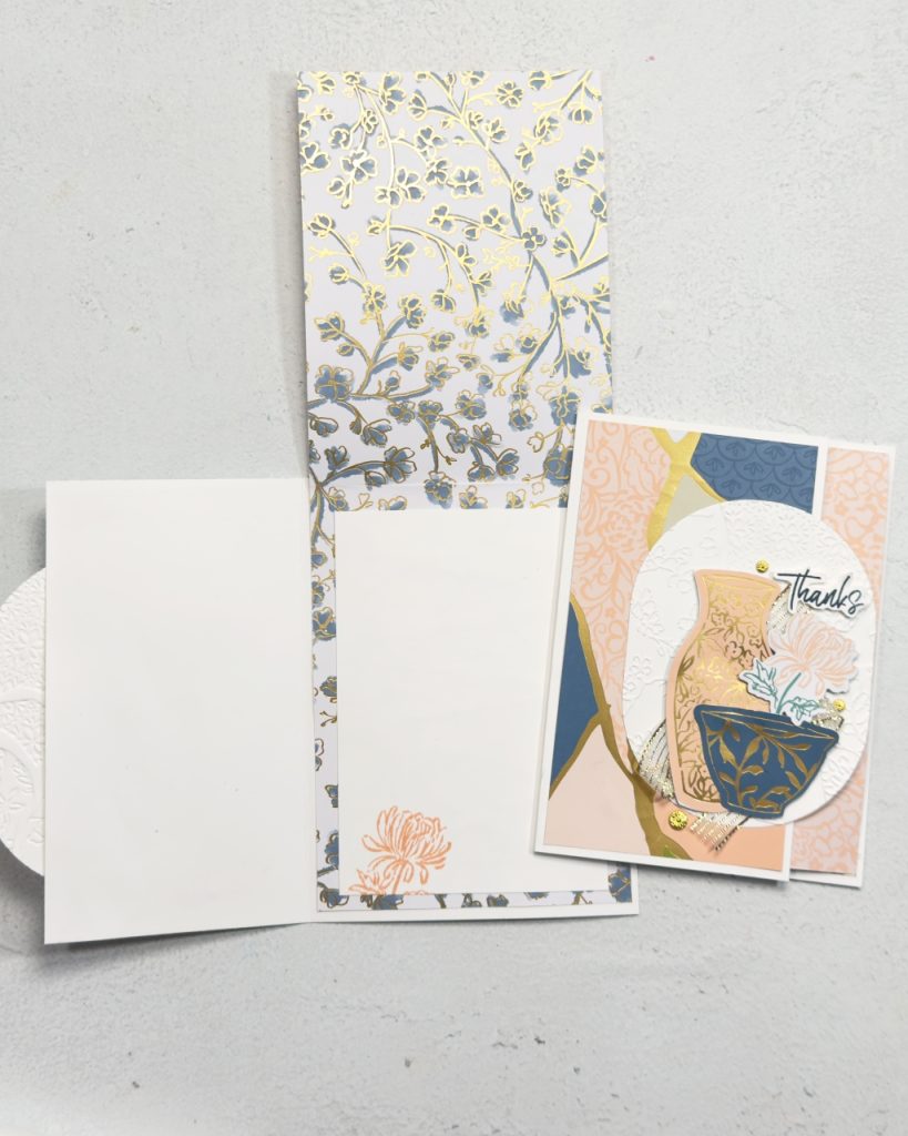A thank you card with pinks and blues Japanese style. The is a patterned vase and cup and flowers on top of some beautiful patterned papers.