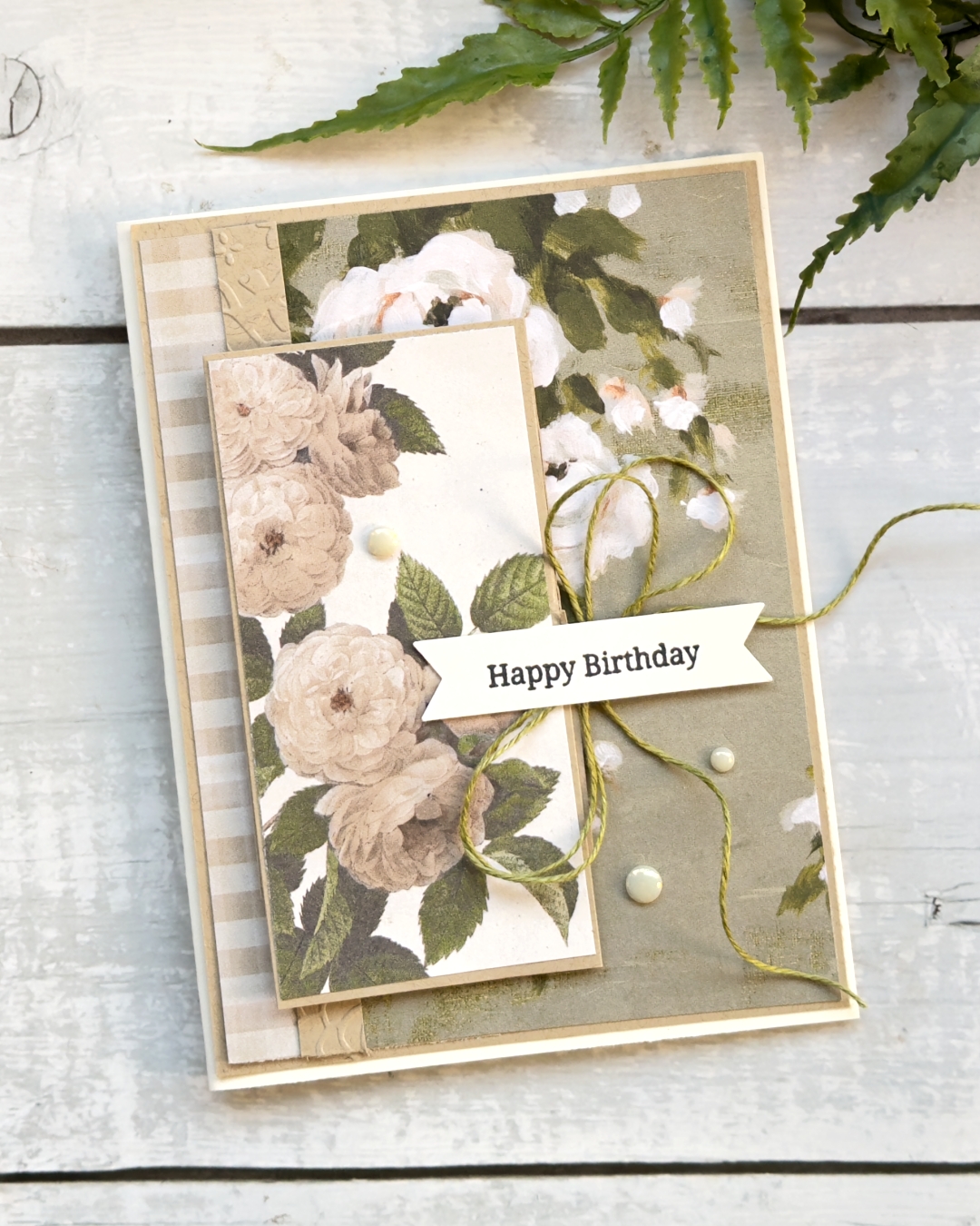 A Birthday card in Very Vanilla and crumb Cake soft Hues. On the front is some old fashioned White Roses
The sentiment reads Happy Birthday and there is a large green linen bow beneath. There is 3 white gems to finish