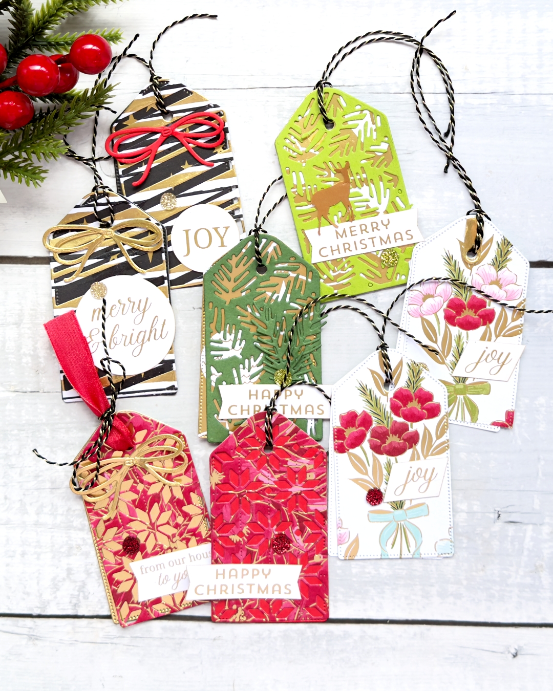 * Christmas tags in Reds, White and Greens Each has a black and gold thread on the top and a gold and white sentiment saying happy Christmas.