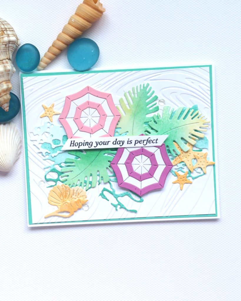 Handmade coastal card using Rolling Waves Bundle with embossed background, ink blended tropical leaves, layered umbrellas, and beach elements, perfect for summer cardmaking inspiration.