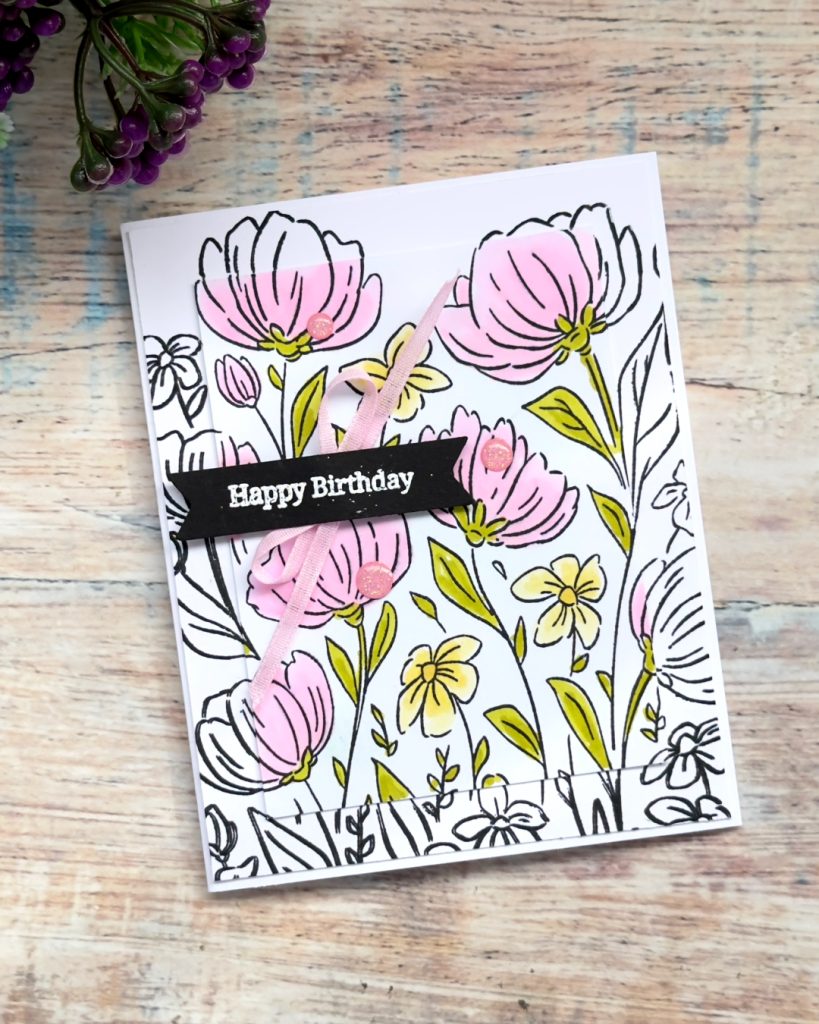 Handmade floral birthday card created with the Flowers Fair background stamp using a spotlight layering technique, soft pink colouring, ribbon detail, and stamped sentiment banner.
