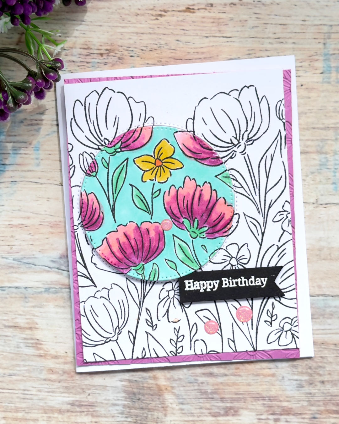 Handmade birthday card using the spotlight technique with the Flowers Fair background stamp, featuring a coloured floral circle focal point on a black and white stamped background.