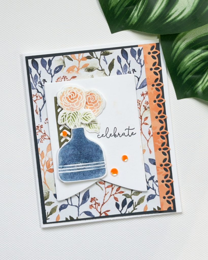 Handmade floral card with blue vase, peach flowers, patterned background and “celebrate” sentiment using the Pop-Up Petals bundle.