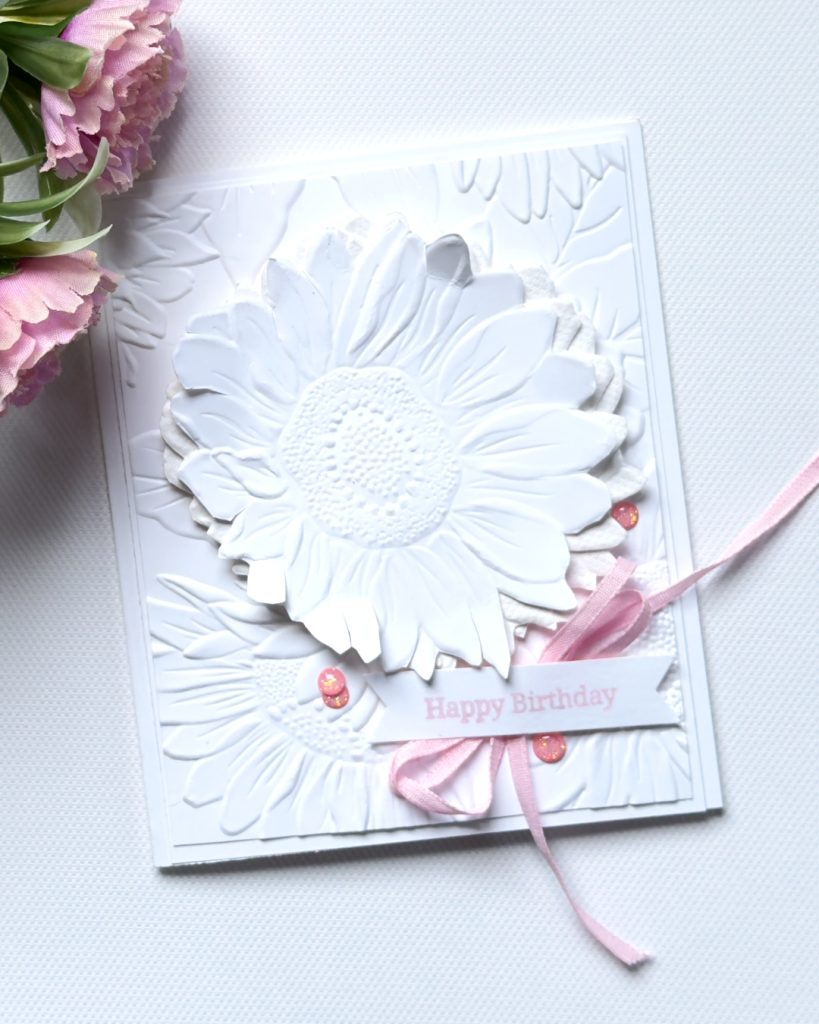 White-on-white handmade sunflower birthday card with layered embossed petals, soft pink ribbon, and subtle embellishments for an elegant look.