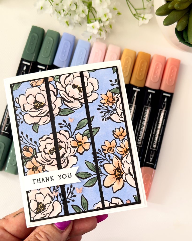 Handmade thank you card with Artisan Sketched Garden floral background coloured in blue and warm tones using Stampin’ Up! 2026–2028 In Colours, with black strip accents and a simple thank you sentiment.