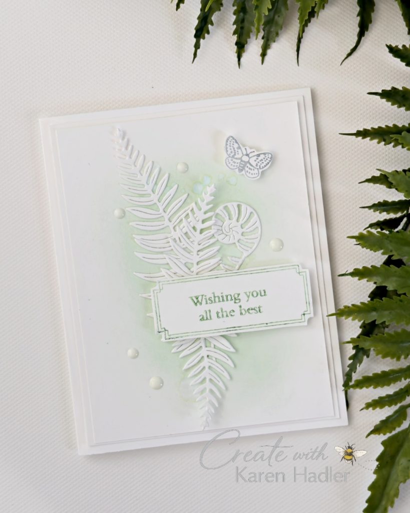 Elegant white handmade card with layered fern die cuts, soft green ink blending, pearl embellishments, a moth accent and a “Wishing you all the best” sentiment.